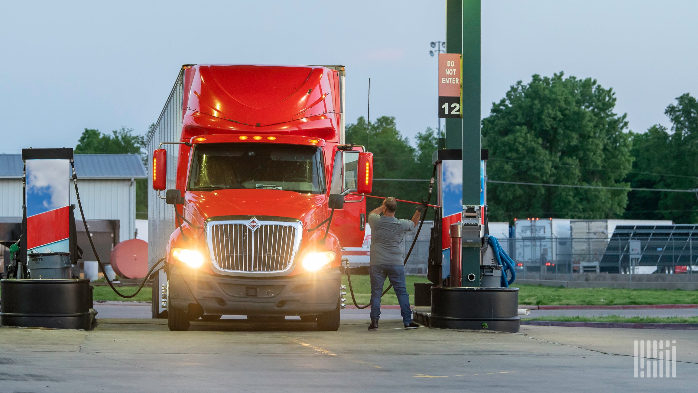 1773068881846_A truck driver cleaning windows while fueling